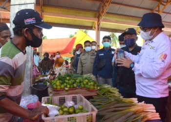 Bupati Hamim Pou memperlihatkan aplikasi QRIS di smartphone kepada salah seorang pedagang di Pasar Jumat Kabila, Jumat (16042021). (F.AKPDiskominfo)