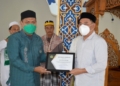 Bupati Hamim Pou menerima penghargaan Sertifikat Apresiasi dari Menteri Agama RI, Yaqut Cholil Qoumas yang diserahkan perwakilan Penyuluh Agama Kemenag Bone Bolango, Sunaryo Usman, Jumat (3/12/2021). (F.AKP/Diskominfo)
