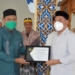 Bupati Hamim Pou menerima penghargaan Sertifikat Apresiasi dari Menteri Agama RI, Yaqut Cholil Qoumas yang diserahkan perwakilan Penyuluh Agama Kemenag Bone Bolango, Sunaryo Usman, Jumat (3/12/2021). (F.AKP/Diskominfo)