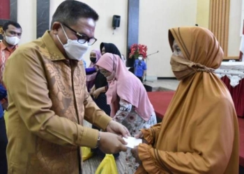Wali Kota Gorontalo, Marten Taha saat menyerahkan paket logistik ke salah satu warga