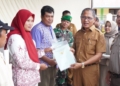 Sekda Kota Gorontalo, Ismail Madjid saat menyerahkan sertifikat tanah ke 83 warganya. (dok. humas)