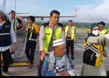 Kapolsek Kawasan Bandara Djalaluddin Gorontalo, Iptu Ismet Ishak saat membantu salah satu jemaah haji asal Kota Gorontalo. (foto. pkbdg/nn)